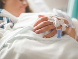 a woman laying in a hospital bed with an iv in her hand